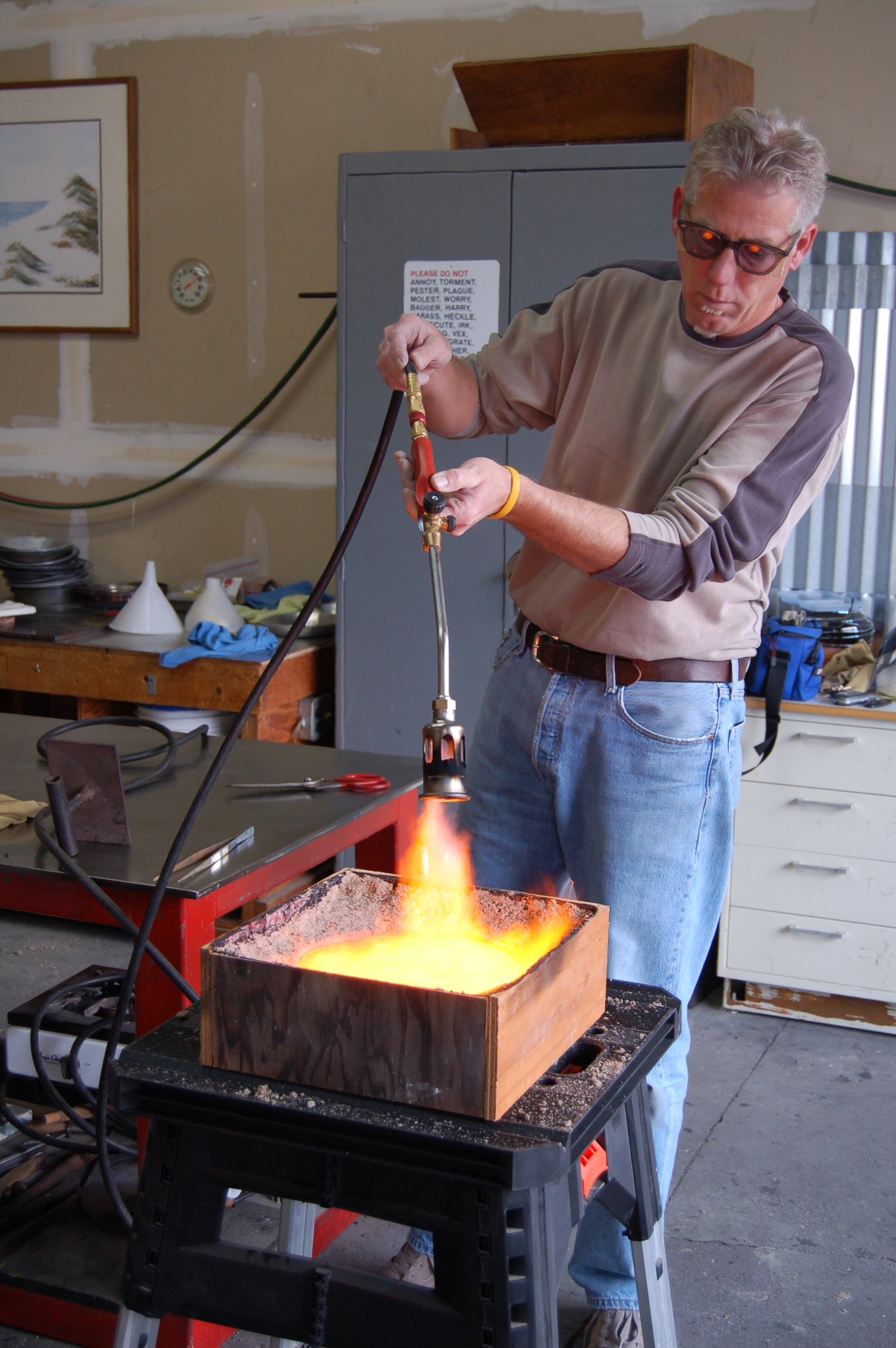Keith S. Bramer casting molten glass with a torch in the studio